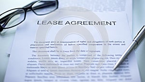 Lease agreement lying on table, pen and eyeglasses on official business document photo