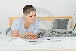 leasure and home concept - smiling middle-aged woman reading book and lying on couch at home.