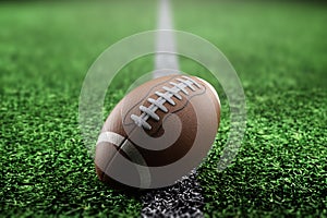 Leather American football ball on the grass of a football field at the stadium. American sport concept, strength, victory. Poster