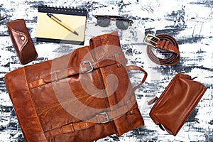 Leather backpack and accessories on a gray table. Stylish brown leather accessories close-up. View from above