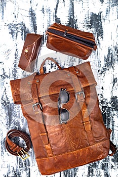 Leather backpack and accessories on a gray table. Stylish brown leather accessories close-up. View from above