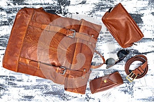 Leather backpack and accessories on a gray table. Stylish brown leather accessories close-up. View from above