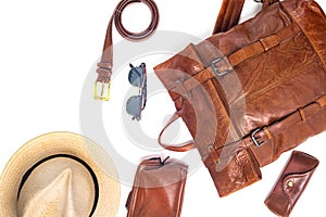 Leather backpack, hat, and accessories on white background. Stylish brown leather accessories close-up. View from above