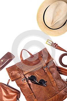 Leather backpack, hat, and accessories on white background. Stylish brown leather accessories close-up. View from above