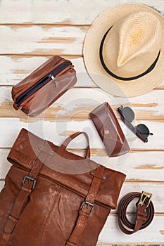 Leather backpack, hat and accessories on a white table. Stylish brown leather accessories close-up. View from above