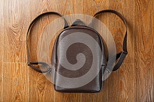 Leather backpack or satchel made of brown leather on a wooden background