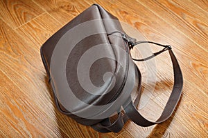 Leather backpack or satchel made of brown leather on a wooden background