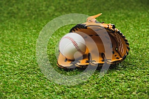 Leather baseball glove and ball on green grass