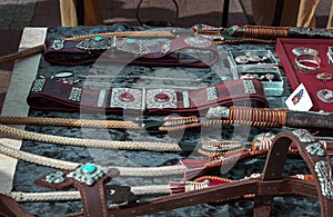 Leather belts inlaid with silver and stones, riders` whips, handmade horse harness in traditional Asian style lie