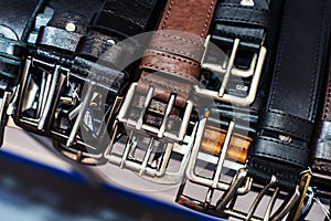 Leather belts with metal buckles on the counter in the store. Close-up