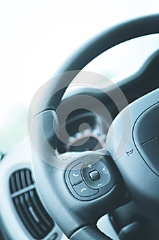 Leather-black steering wheel with remote control, modern car, blurry dashboard