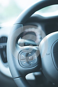 Leather-black steering wheel with remote control, modern car, blurry dashboard