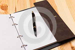 Leather-bound business notebook with a Parker pen on wooden background. Business concept
