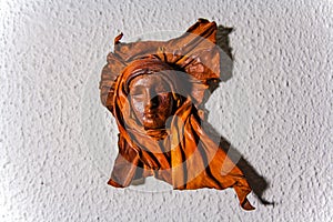 Leather bust decor on the wall at home. decor in form of face of a nun in veil or wimple photo