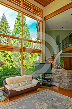 Leather couch and TV set in front of huge window in living room