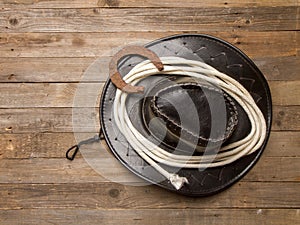 leather cowboy hat with lasso and horseshoe on rough wooden table