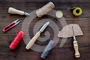 Leather craft accessories. Tools and matherials on dark wooden background top view