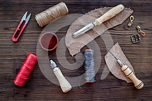 Leather craft accessories. Tools and matherials on dark wooden background top view