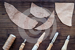 Leather craft accessories. Tools and matherials on dark wooden background top view