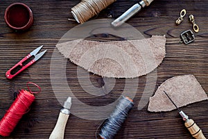 Leather craft accessories. Tools and matherials on dark wooden background top view
