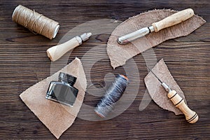 Leather craft accessories. Tools and matherials on dark wooden background top view