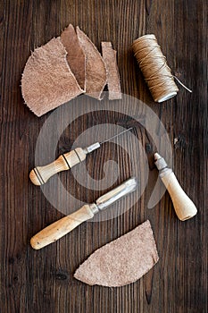 Leather craft accessories. Tools and matherials on dark wooden background top view