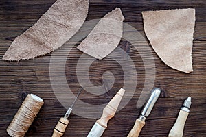 Leather craft accessories. Tools and matherials on dark wooden background top view