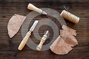 Leather craft accessories. Tools and matherials on dark wooden background top view