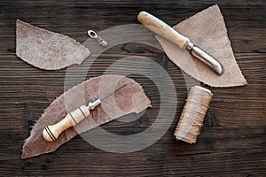 Leather craft accessories. Tools and matherials on dark wooden background top view