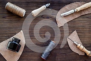 Leather craft accessories. Tools and matherials on dark wooden background top view copyspace