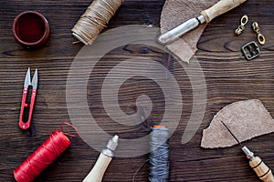 Leather craft accessories. Tools and matherials on dark wooden background top view copyspace