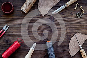 Leather craft accessories. Tools and matherials on dark wooden background top view copyspace