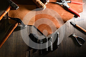 Leather craft or leather working. Leather working tools and cut out pieces of brown leather on craftman`s work desk