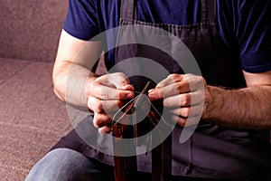 leather craft tailoring process - men's hands sewing brown wallet