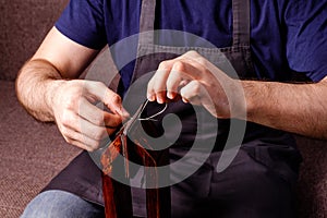 leather craft tailoring process - men's hands sewing brown wallet