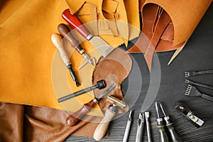 Leather with craft tools on dark wooden background