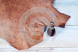 Leather craft tools on a wooden background. Leather craftmans work desk . Piece of hide and working handmade tools on a work table