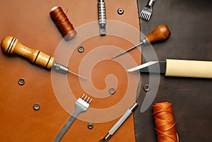 Leather crafting DIY tools lies on natural brown leather.