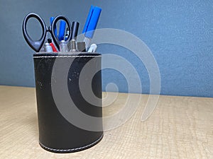 A Leather Cylindrical Black Pencil Case Filled with Writing Tools