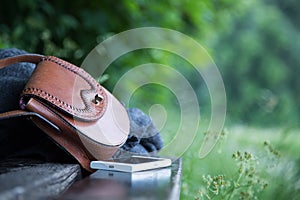 Leather handbag, smartphone and jacket on a park bench, nobody