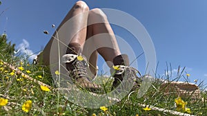 Leather hiking shoes of young Caucasian woman lying down and taking a rest in the grass on a mountain peak with blue sky and cloud