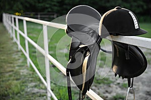 Leather horse saddle and helmet on wooden fence