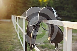 Leather horse saddle and helmet on wooden fence outdoors