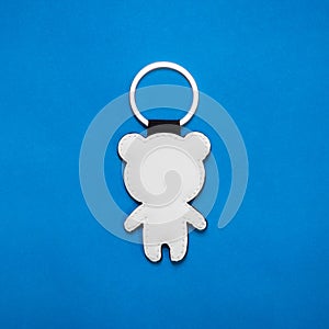 Leather key ring in bear shape on blue paper background. Blank key chain for your design