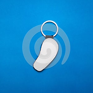 Leather key ring in curve shape on blue paper background. Blank key chain for your design