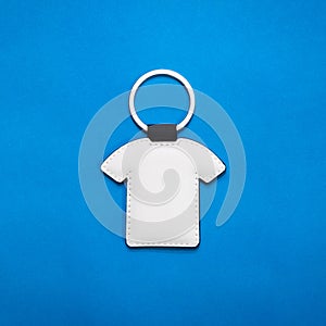 Leather key ring in shirt shape on blue paper background. Blank key chain for your design