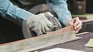 A leather master is dying leather belt edges with fire. Working process of the leather belt in the leather workshop.