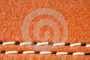 Leather is natural orange, seam is made of white threads, close-up macro view