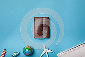 Leather journal on minimal blue background with plane and other items