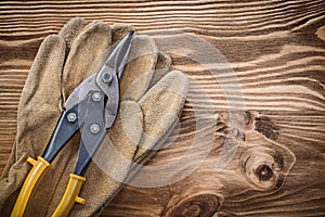 Leather protective gloves tin snips on wooden board construction